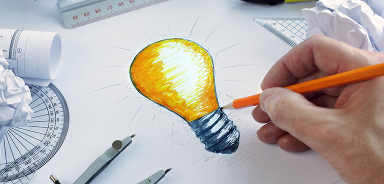 a hand is seen sketching a light bulb