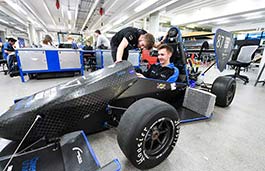 Students working on a sports racing car in an engineering suite 