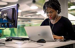 Student wearing headphones looking at a laptop 