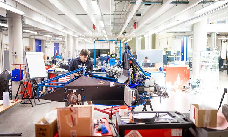 Students working on a motor racing car in an engineering suite