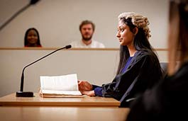 Female student wearing a judges wig in a mock court room.