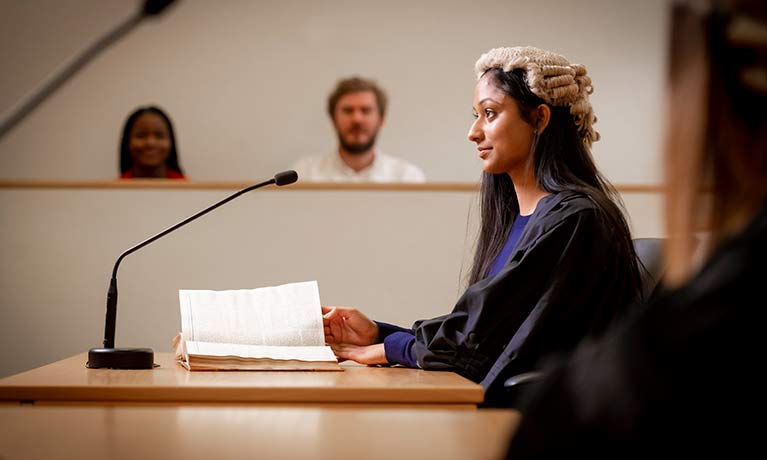 Female student wearing a judges wig in a mock court room