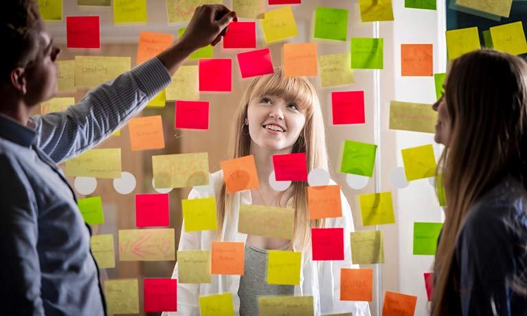 Marketing student looking up at a perspex wall covered in postits