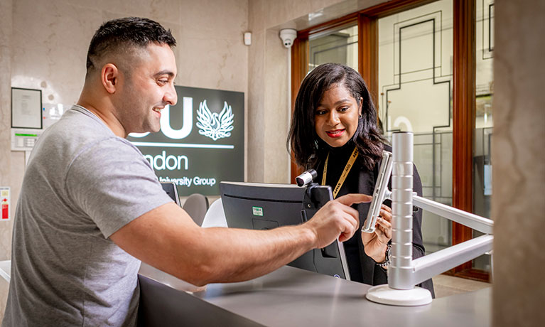 Student pointing at a device showing a member of staff
