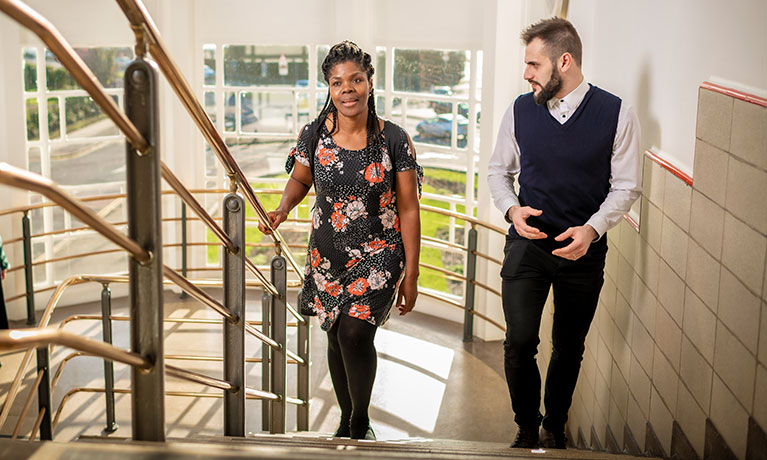 Two people walking up a flight of stairs talking