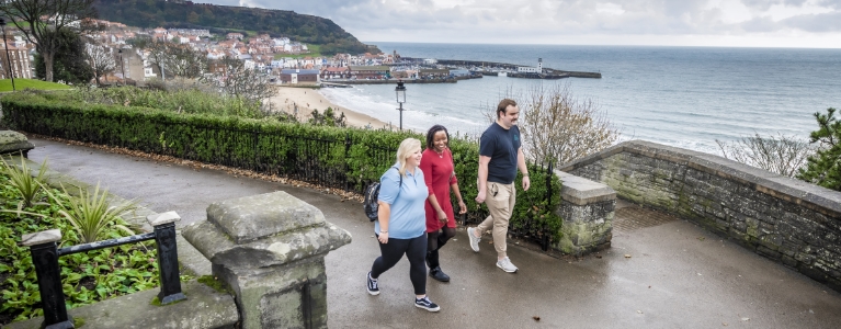 Three people walking with the Scarborough beach in view