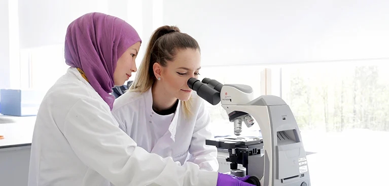 2 females in a laboratory looking into a telescope