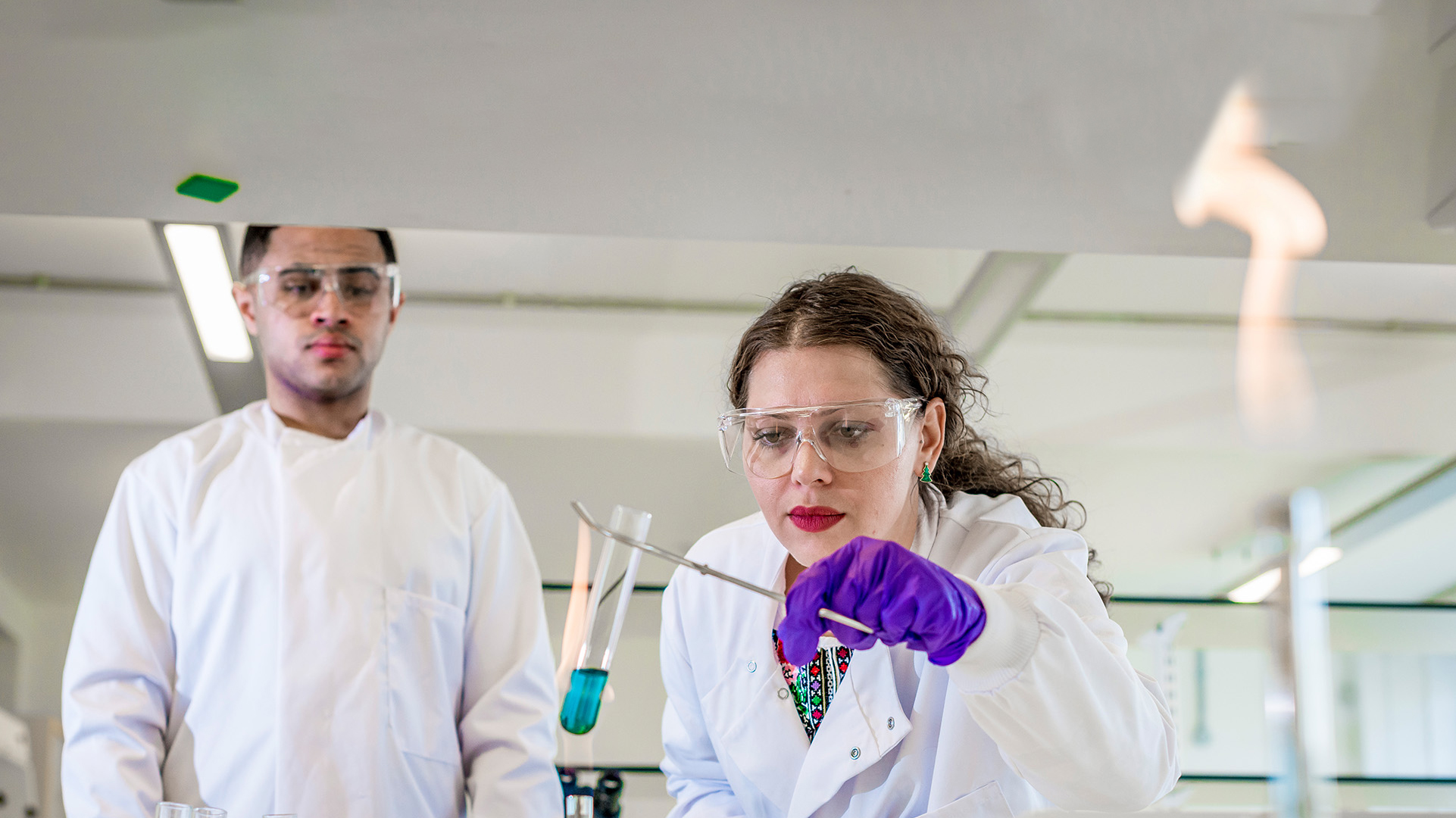 Two Applied Biosciences students in a laboratory using a bunsen burner