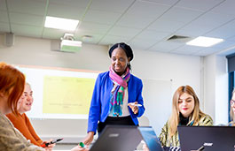 Female lecturer stood at the front of a classroom with students