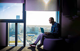 Student sat next to a window working on their laptop