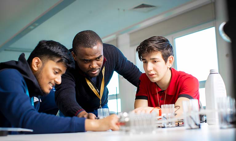 Lecturer helping two students in a classroom