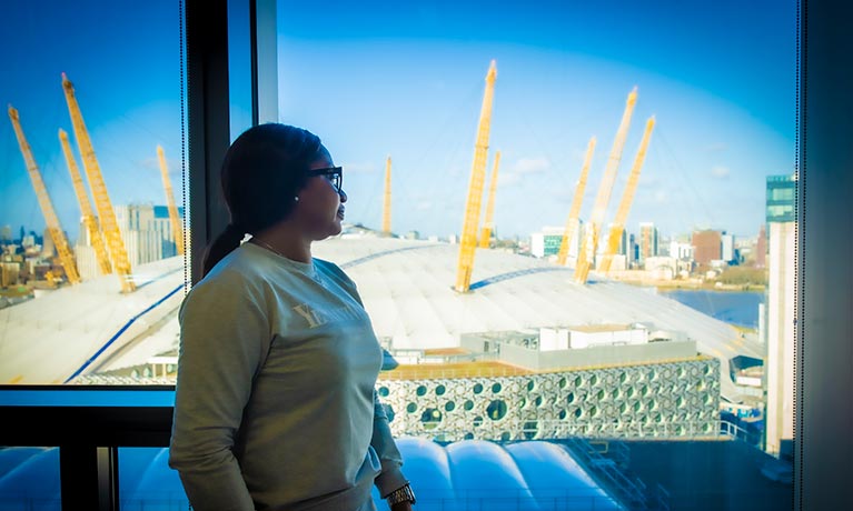 Female stood by a window looking out to the 02 Arena