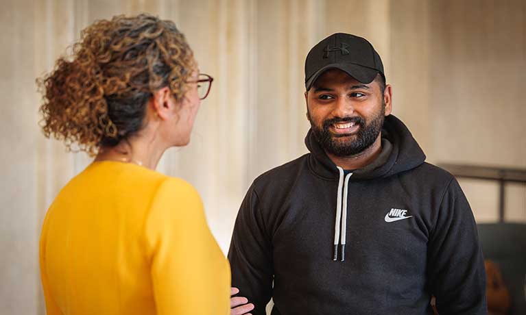 A student talking to a lecturer with a yellow jumper