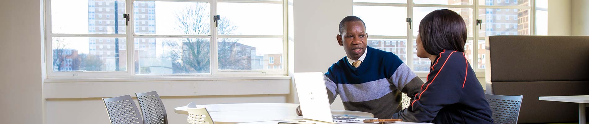 Two people sat at a desk with an open laptop