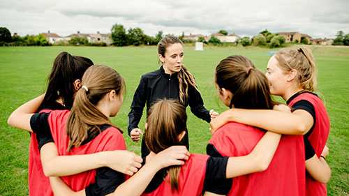 Sport & Leisure Management class gathered around a tutor on a sport field, preparing for a game