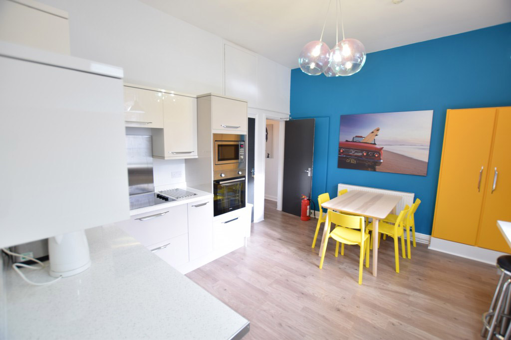 Kitchen area with a dining table and chairs against a bright blue wall