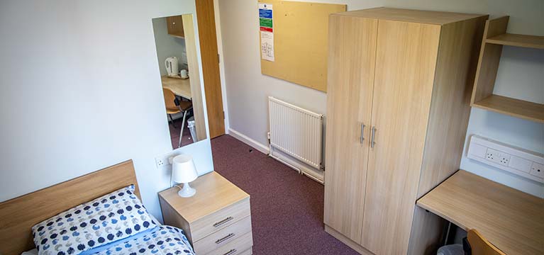 Bedroom with a desk in the corner and wardrobe alongside a bed and mirror 