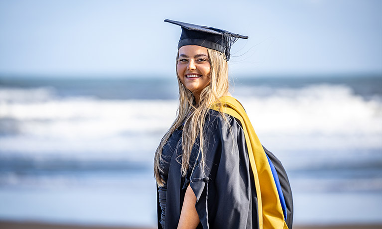 Girl smiling during her graduation  ceremony next to the sea