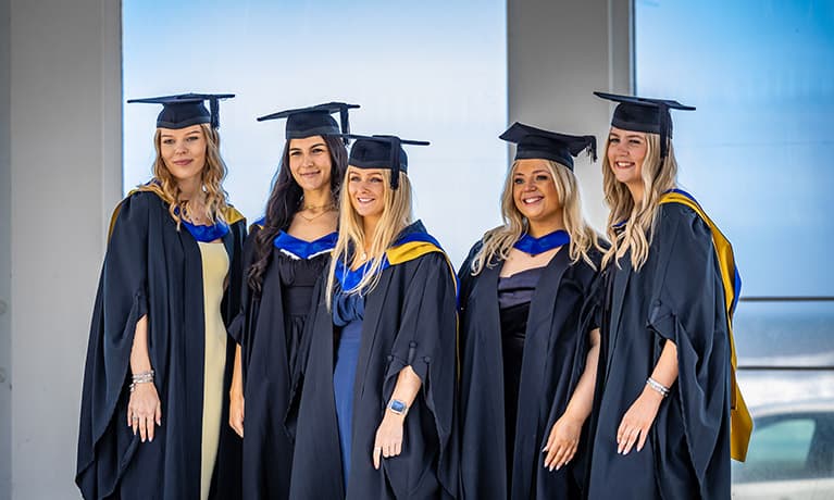 Group of female graduates smiling in their gowns and caps