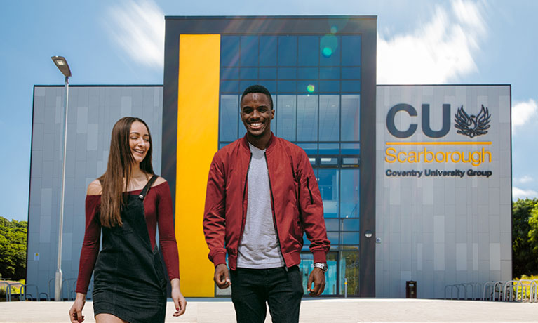 male and female student walking with Scarborough university building in the background