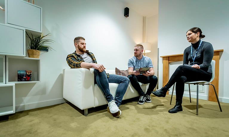 three people sitting and conversating in a quiet room.