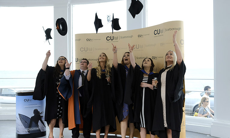 Students throw mortarboards into the air