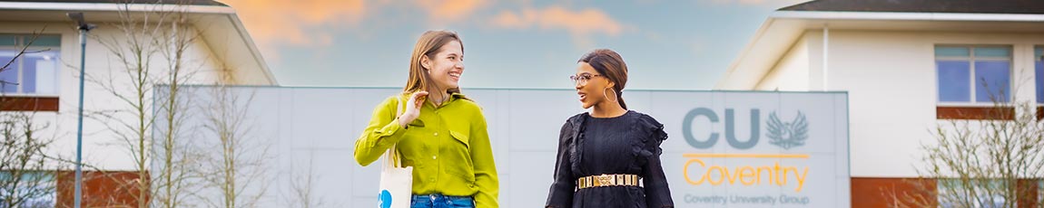 Two female students walking away from the CU Coventry building