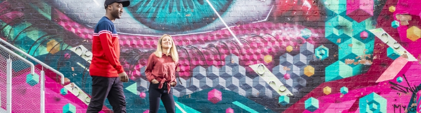 Students walking in front of graffiti