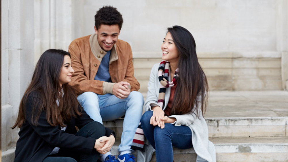Three Applied Psychology students sat talking on steps