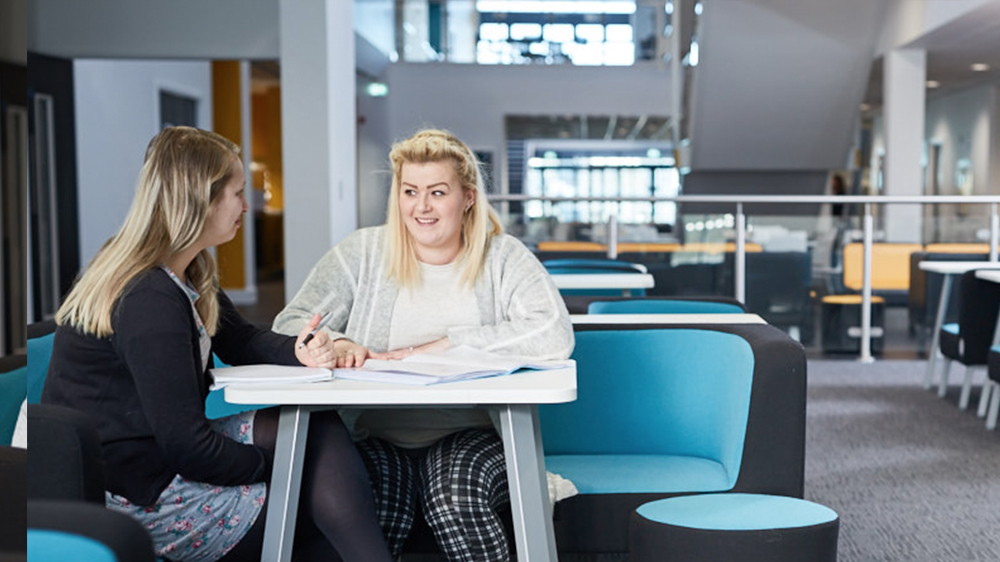 Two Health & Social Care students studying together at a desk
