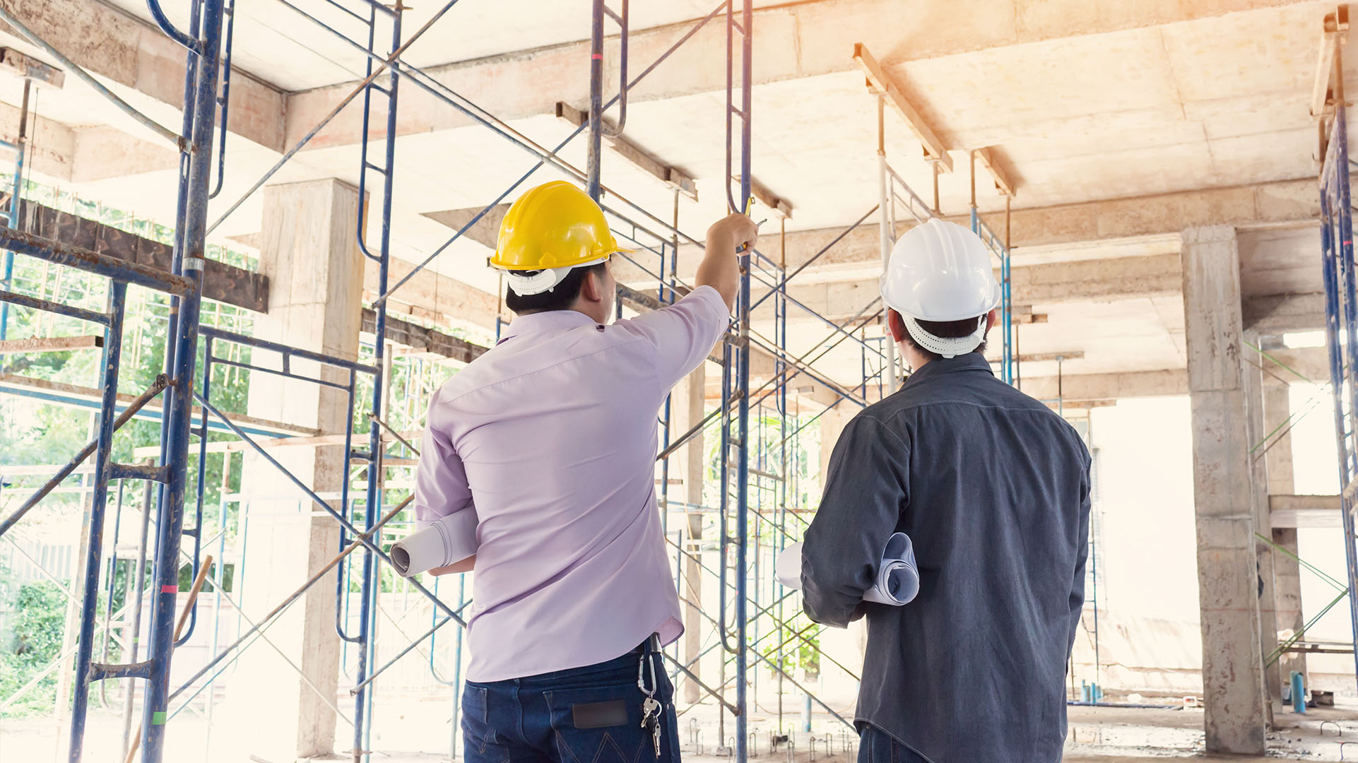 Two Building students wearing hard hats on an indoor construction 