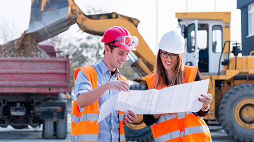 Two Civil Engineering students examining blueprints at a building site