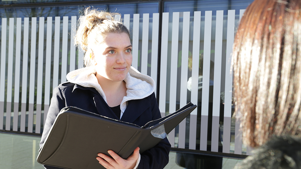 A student with a clipboard interviewing someone