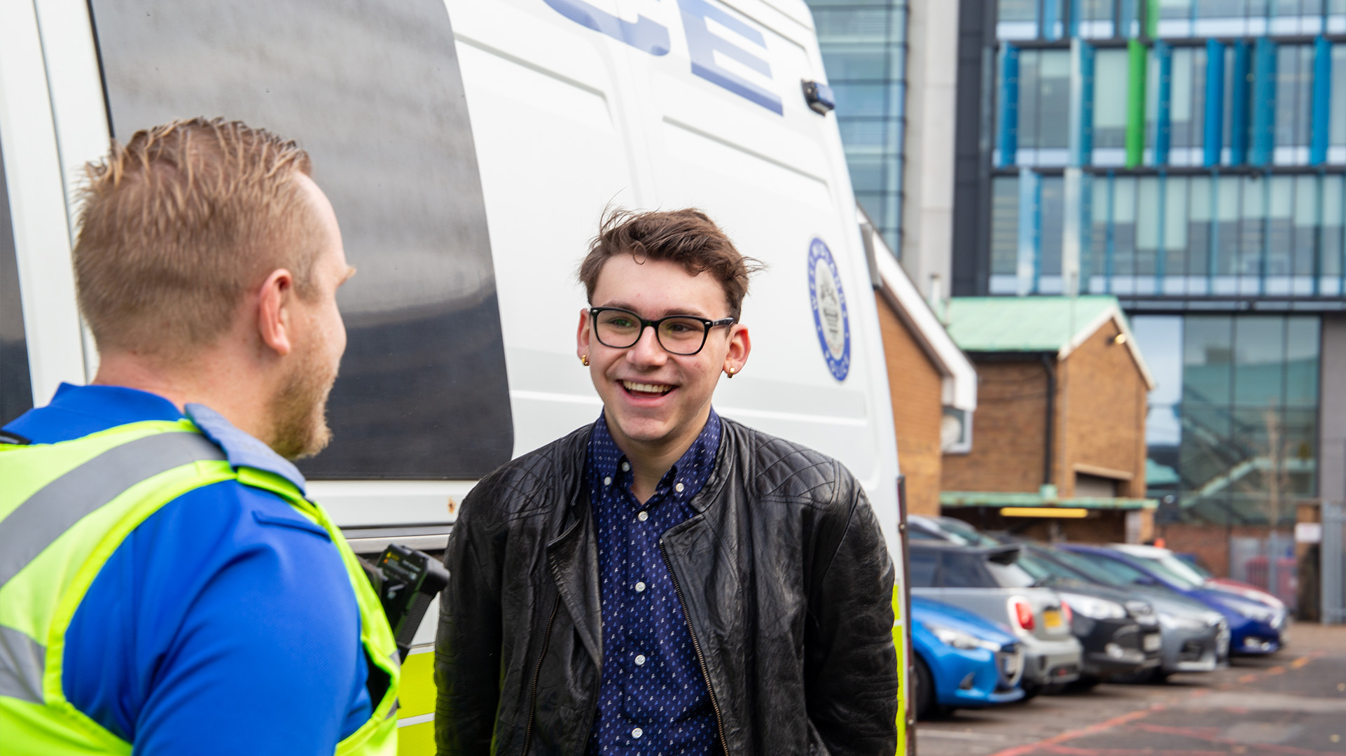 A Policing student talking to a police officer beside a police van