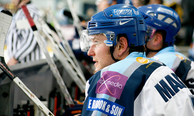 Ice hockey player watching the match from the sideline