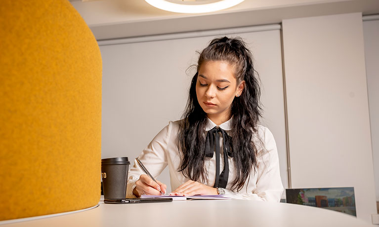 Student sat at a desk writing in a book