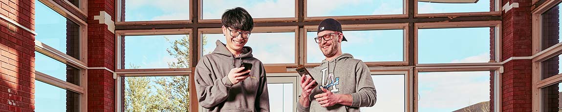 Two male students stood looking at their phones