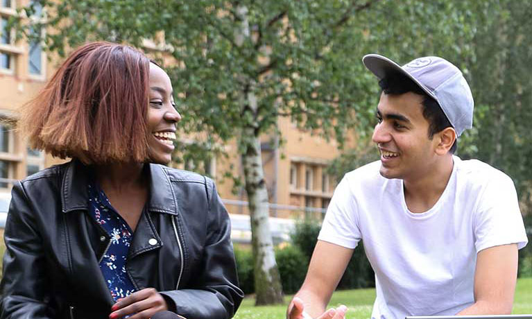 Two students sat outside talking to each other