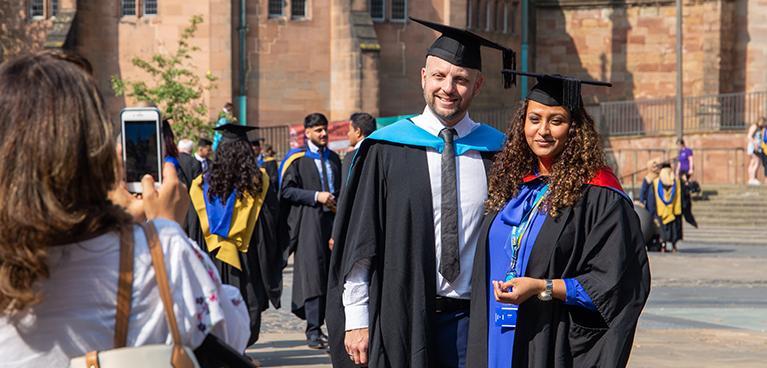 Student with her tutor getting photo taken outside Coventry Cathedral