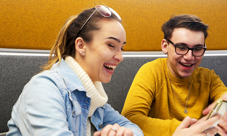 Two students sat together smiling