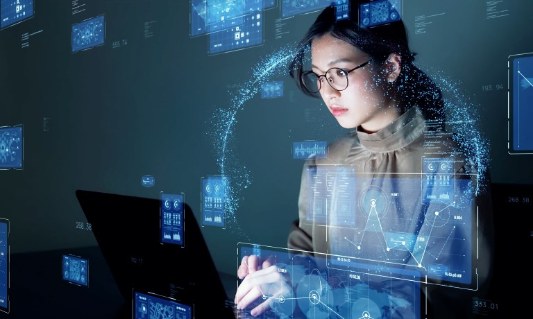 Female sitting in a dark room working on a laptop 