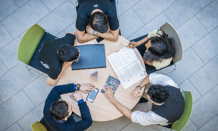 Birds eye view of a group of students sitting around a desk 