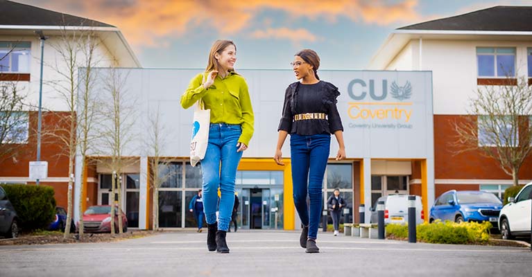 Two students walking away from the CU Coventry building