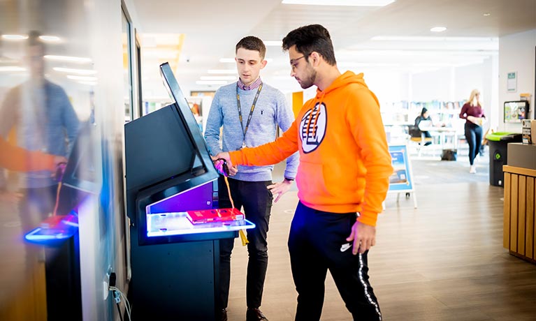 Student using a touchscreen with a lecturer helping