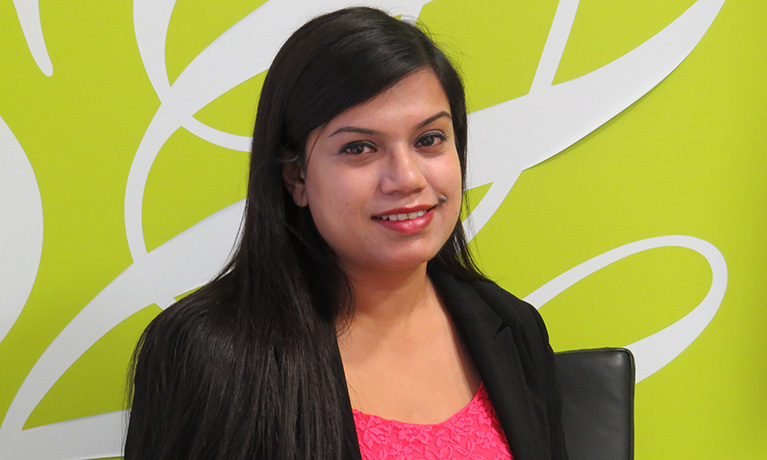 Brunette young lady smiling while sitting in front of a distinctive green wall.