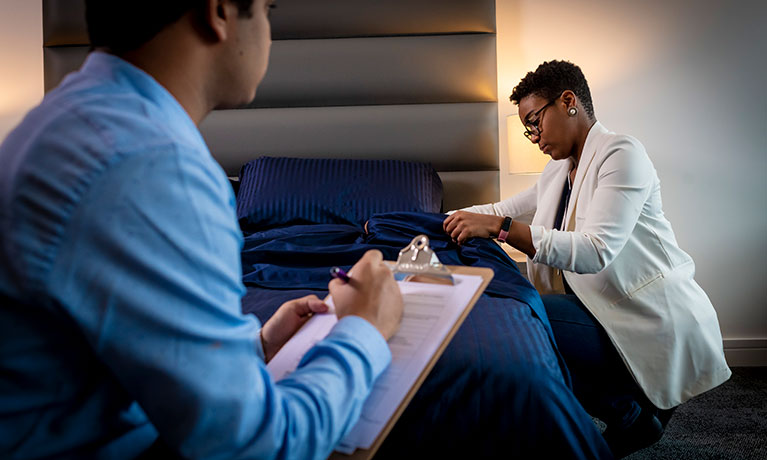 Female inspecting a hotel room while a man is taking notes