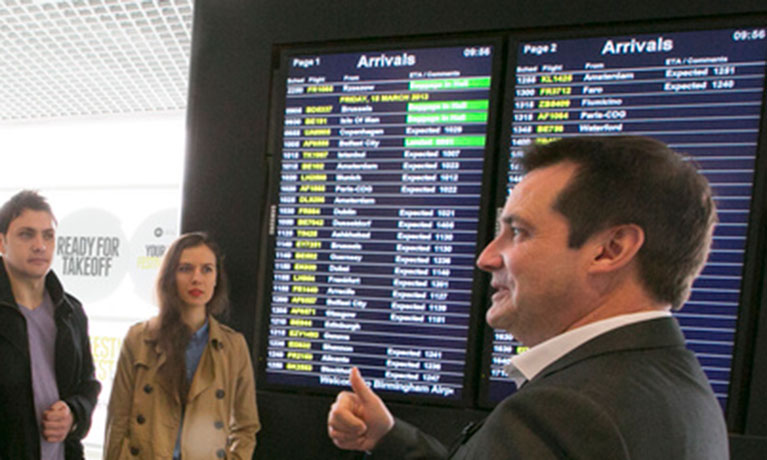 People stood by airport flight time board