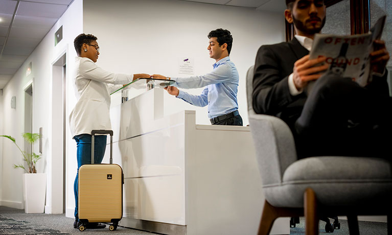 Student picking up keys at reception desk 