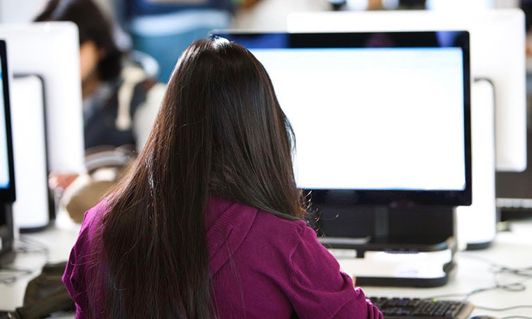 female sat in front of a mac screen