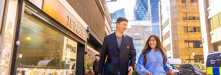 Male and female walking down a London street smiling 